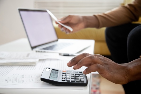 person using calculator with laptop in background