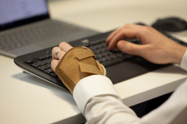 Person wearing a wrist support while typing on a computer keyboard at a desk.
