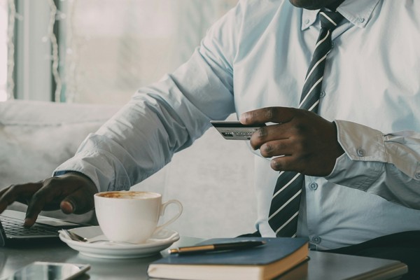 A professional sits at a desk using a laptop while holding a bank card, representing the management of personal injury claim funds and compensation.
